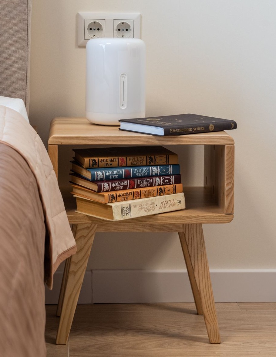 Light wood-tone bedside table with an open shelf and splayed legs