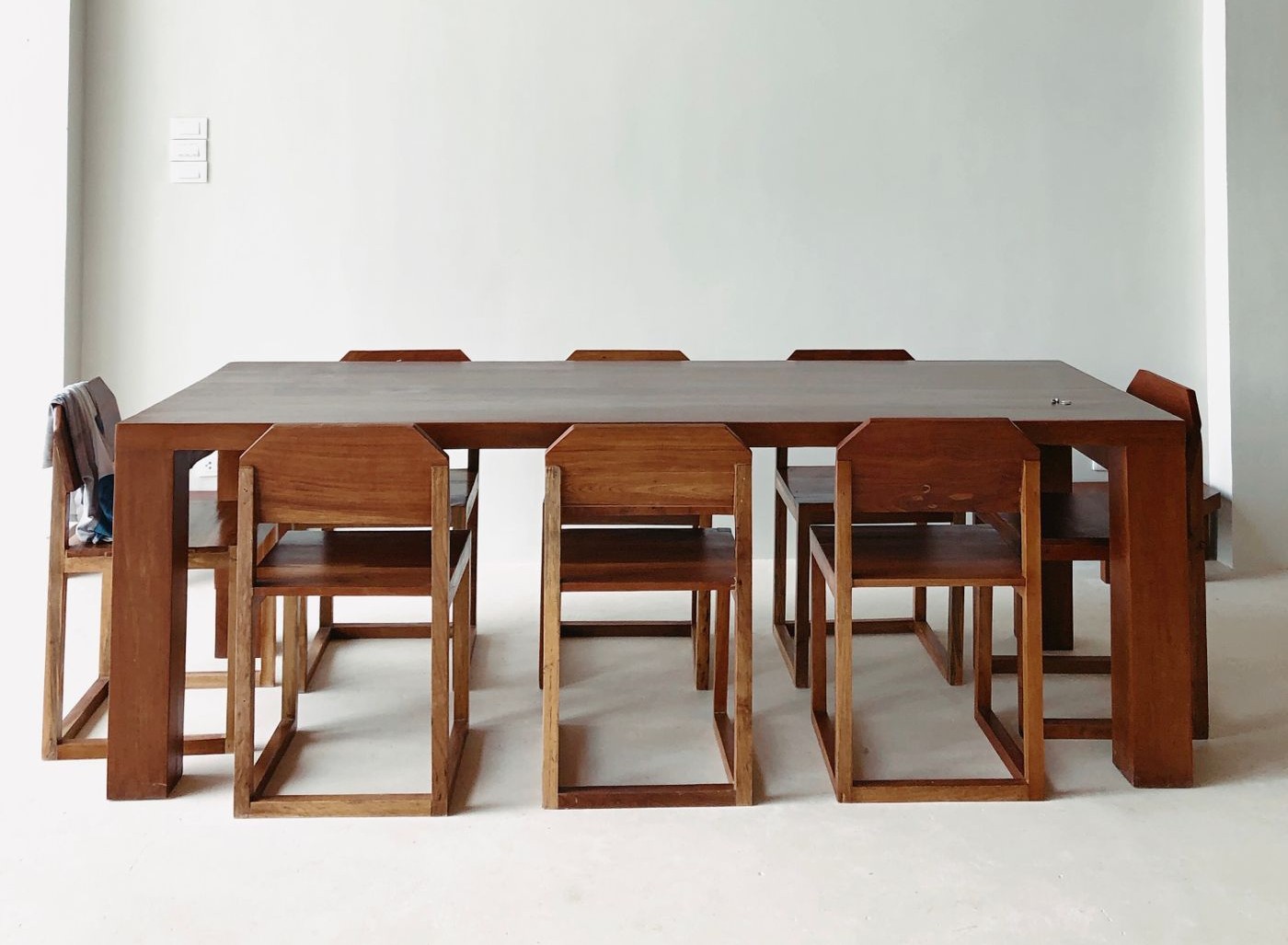 Rectangular dining table with a light top and brown square legs; chairs shown for styling