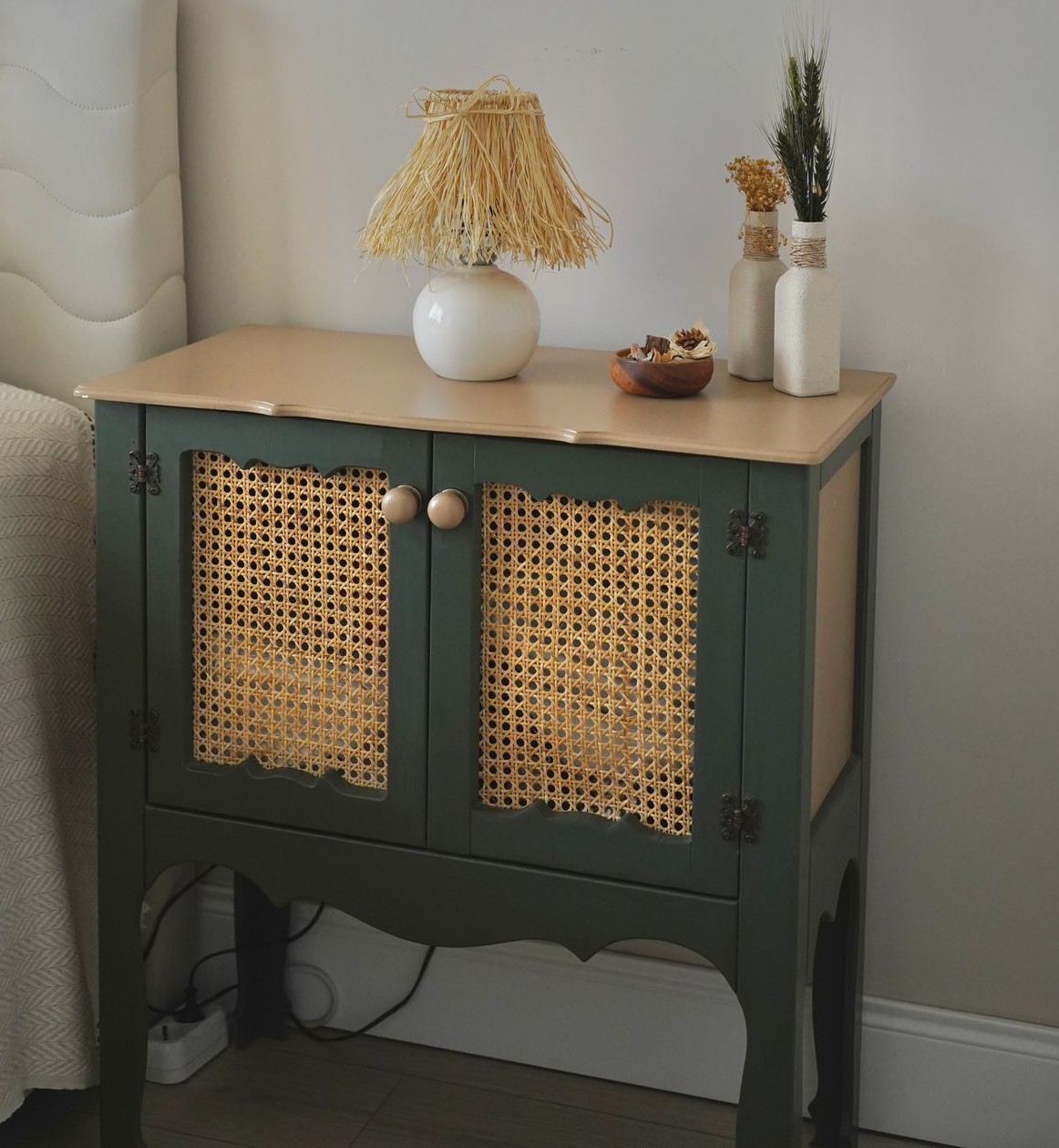 Dark green bedside cabinet with two woven-panel doors and a light top
